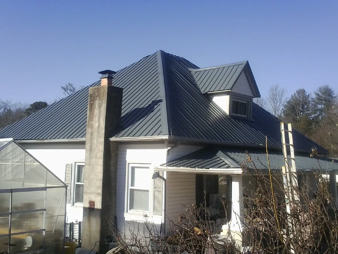Dark blue standing seam metal roof on a white farmhouse with dormer — Slate & Tile Roof Repair by Roofing Brothers in Citrus Heights