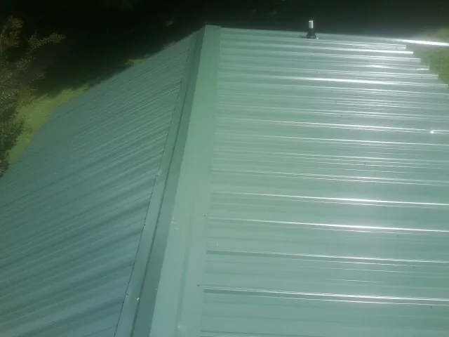 New green metal panels meeting at the ridge of a roof — Flat Roof Repair work by our crew in Citrus Heights
