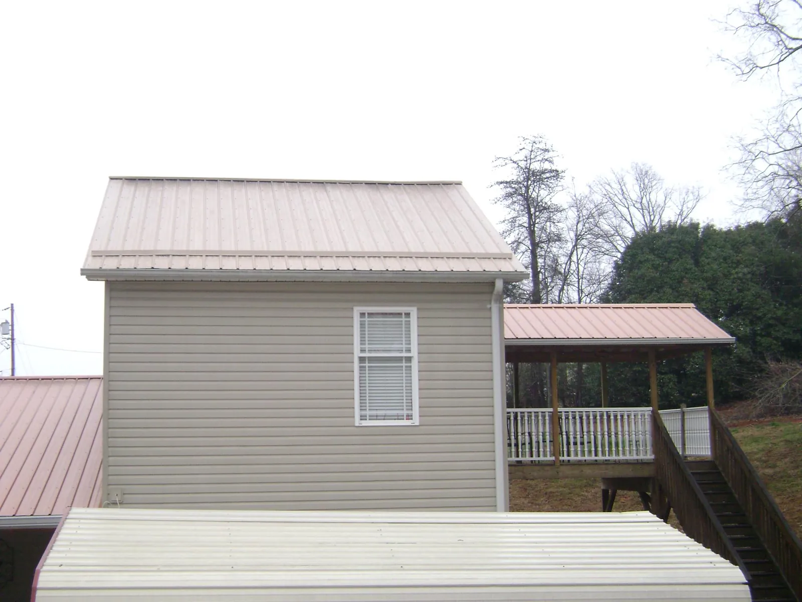 Tan metal roofs on a two story addition and attached porch, from a Roof Replacement job in Citrus Heights