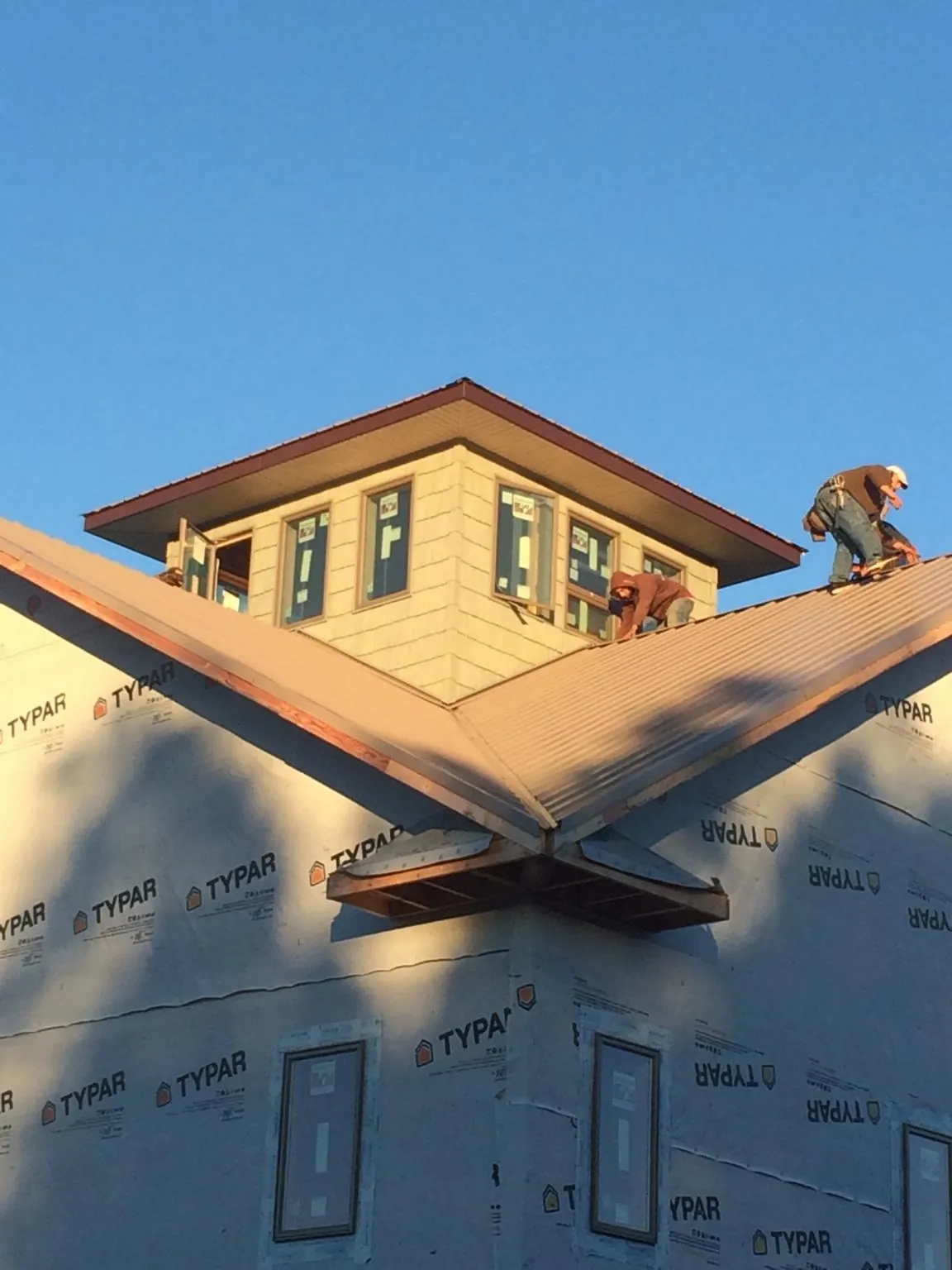 Roofers working around a rooftop cupola on a new metal roof at sunset — Roof Waterproofing in Citrus Heights by Roofing Brothers